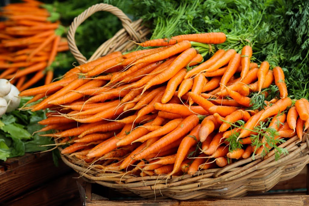 Vibrant orange organic carrots displayed in a wicker basket at a local Prague market.